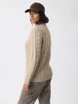 Sweater de tejido grueso con textura trenzada, cuello alto y mangas largas.