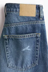 Jean tobillero de cinco bolsillos en denim de algodón, de tiro alto con piernas rectas y detalles de roturas sutiles.