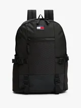 Mochila estilo retro de la marca Tommy Jeans, color negro, inspirada en modelos utilitarios. Cuenta con compartimento principal con cierre de cremallera, bolsillo exterior con cremallera, panel delantero con textura acolchada y parche con el logo de la marca en la parte superior. Incorpora correas ajustables, asa superior y detalles de tiras trenzadas.
