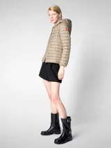 Campera puffer beige con capucha, cierre frontal con cremallera naranja, bolsillos laterales ocultos y logo de goma en la manga. Confeccionada en nylon liviano y con puños y dobladillo elásticos de Lycra.