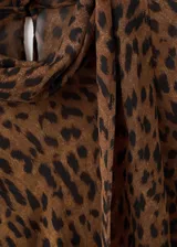 Blusa de manga larga acampanada con estampado de leopardo, cuello redondo y detalle de fular integrado en el cuello.