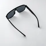 Lentes de sol tipo escudo con armazón de policarbonato marrón oscuro y detalles metálicos dorados en las patillas, con cristales degradados en tonos marrones y protección UV400.