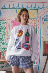 Buzo blanco de corte clásico con cuello redondo y estampado de objetos cotidianos.