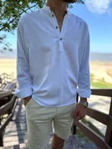 Camisola de lino blanca de manga larga con cuello mao y cierre frontal de botones.