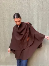 Capa marrón de lana merino con apliques de cuero y tejido de punto trenzado.