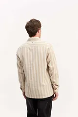 Camisa de manga larga color beige, de tejido texturado con cierre frontal de botones y cuello camisero clásico.