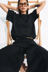 Pantalón de tiro medio confeccionado en lino, con cintura elástica ajustable mediante cordones. Presenta un diseño de pierna ancha con bajo redondeado y aberturas laterales.