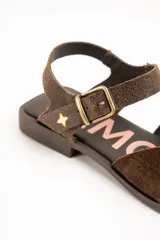 Sandalias de cuero color marrón, estilo romano, con tiras entrelazadas en la parte delantera y tira ajustable al tobillo con hebilla metálica.