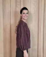 Camisa de manga larga con diseño de rayas verticales y bordados sutiles. Presenta cuello redondo, cierre frontal con botones y mangas abullonadas con volados en los hombros.