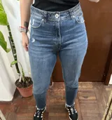Pantalón jean de tiro alto en color azul con sutiles roturas y dobladillo desmechado.