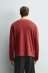 Camiseta de manga larga con cuello redondo, corte relajado y diseño de rayas horizontales en tonos rojo y negro.