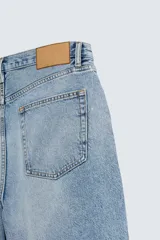 Bermuda de denim de algodón, color verde claro lavado, de corte recto y tiro medio. Presenta cinco bolsillos y cierre frontal con cremallera y botón.