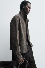Sobrecamisa de corte relajado confeccionada en tejido con viscosa, de color gris oscuro con textura. Presenta cuello subido, cierre frontal con cremallera y bolsillos de vivo en la cadera.