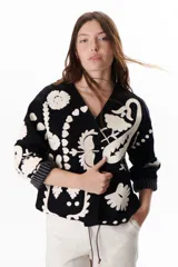 Chaqueta color crudo con bordados florales en tonos rojo, verde y negro.