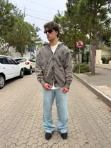 Campera con capucha y cierre frontal, de corte oversize y acabado acid wash en color gris oscuro. Presenta costuras curvas decorativas en el frente y puños acanalados.