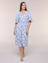 Vestido midi de calce holgado y caída fluida con escote en V cruzado, cintura elastizada fruncida y mangas cortas con volados superpuestos. Cuenta con un diseño estampado de flores grandes en tonos amarillo, blanco, azul marino y verde.