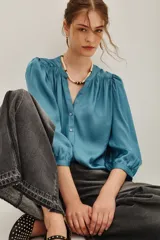 Camisa de viscosa color turquesa, de corte fluido, con cuello mao, escote en V y mangas largas abullonadas con puños elásticos.