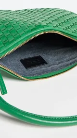 Bandolera verde de cuero tejido con correa de hombro ajustable y cierre de cremallera.