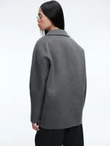 Tapado de paño gris de corte recto y silueta oversized, con solapas clásicas y cierre frontal de doble botonadura.