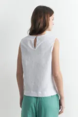 Blusa blanca sin mangas confeccionada en lino, con corte recto y aberturas laterales ajustables con lazos.