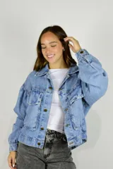 Campera de jean azul de corte oversize, con mangas abullonadas, bolsillos frontales con solapa y cierre de botones metálicos dorados.