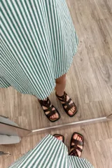 Vestido corto sin mangas con cuello redondo y estampado a rayas verticales verdes y blancas.