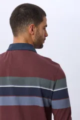 Remera polo de manga larga con diseño de rayas horizontales en tonos azul marino, marrón y gris. Presenta cuello camisero con cierre de botones y puños elásticos en las mangas.