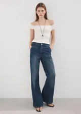 Jeans de denim azul de corte wide leg, tiro medio y diseño clásico de cinco bolsillos con cierre frontal de botón y cremallera.