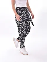 Pantalón tipo babucha de tiro alto, color negro con estampado blanco de motivos abstractos o florales. Posee un lazo o cinturón de tela para ajustar la cintura.
