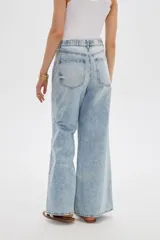 Pantalón jean de corte ancho y tiro alto, con lavado claro y cintura elástica posterior. Presenta bolsillos clásicos y presillas para cinturón.