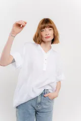 Blusa blanca de lino con escote en V abotonado y mangas cortas arremangadas.