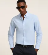 Camisa de manga larga en tejido oxford de algodón color blanco, con cuello tradicional y cierre frontal de botones.