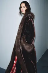 Abrigo largo de terciopelo en tono marrón oscuro, con cuello solapa y puños adornados con aplicación de pelo sintético. Presenta un diseño abierto con forro interior en color rojo con estampado floral.