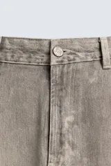 Pantalón de corte relajado confeccionado en tejido de algodón con efecto lavado. Presenta diseño de cinco bolsillos, cierre frontal con cremallera y botón, y detalles de estampados a contraste en la parte delantera y trasera.