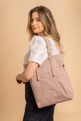 Bolso tipo tote bag de símil cuero color rosa pálido, con asas dobles y detalles de costura en color beige claro. Presenta un bolsillo frontal rectangular aplicado y herrajes metálicos.