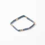 Pulsera elástica compuesta por cuentas rectangulares de color gris azulado intercaladas con pequeñas piezas metálicas doradas.