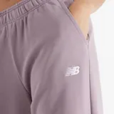 Pantalón de jogging New Balance color lila, con cintura elástica ajustable con cordón, bolsillos laterales y logo bordado en blanco.