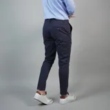 Pantalón de gabardina color azul marino, de corte ajustado y tiro medio, con cierre y botón frontal.