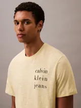 Remera color crema de algodón con cuello redondo y mangas cortas con dobladillo. Estampado vertical con el logo de Calvin Klein Jeans en el frente.
