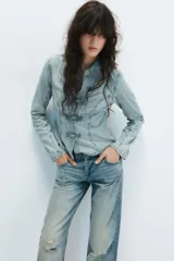 Camisa de denim celeste con cuello solapa, manga larga y cierre frontal con nudos de tela.