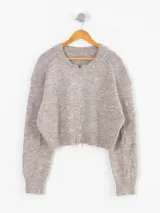 Cardigan de punto color beige, con cierre frontal completo, cuello redondo y diseño cropped con puños y ruedo acanalados.