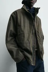 Parka de algodón con acabado lavado, color verde oscuro, de corte relajado. Presenta cuello subido, cierre frontal oculto por solapa con botones a presión, bolsillos de vivo en el pecho y bolsillos plastrón en la cadera.