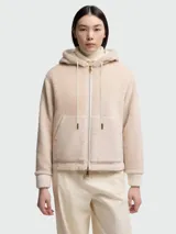 Buzo con capucha de tejido afelpado color beige claro, con cierre frontal de cremallera y bolsillos canguro. Presenta puños y bajo acanalados.