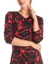 Vestido corto de seda fría con estampado floral en tonos rojo y negro. Presenta cuello volcado, mangas tres cuartos y un detalle de drapeado lateral en la cintura.