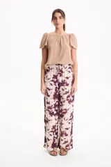 Blusa de manga corta con pliegues en escote redondo, confeccionada en tela crepé de color beige.