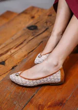 Bailarina de diseño artesanal confeccionada en rejilla bordada con motivo de flores pequeñas, con refuerzo en el talón de ante color camel y ribete a juego. Presenta un detalle de media esfera metálica dorada en la puntera y suela plana de cuero.