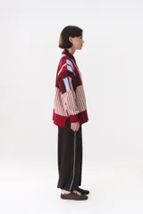 Buzo de tejido de punto con diseño de bloques de rayas verticales en colores rojo, verde, bordó y crema. Presenta cuello alto, corte oversize y terminaciones en rib en puños y ruedo.