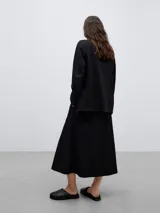 Blazer sastre negro tejido de lana merino, sin solapa y sin bolsillos, de largo bajo cadera y efecto emboss.