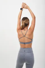 Top deportivo color beige con contorno inferior y tiras cruzadas en la espalda color borgoña. Cuenta con almohadillas removibles.