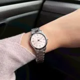Reloj análogo Casio para mujer, con caja y brazalete de acero inoxidable plateado. Presenta una esfera redonda color rosa con índices aplicados, incluyendo números romanos en las posiciones de las 12, 6 y 9. Indica resistencia al agua de 50 metros (WR 50M).
